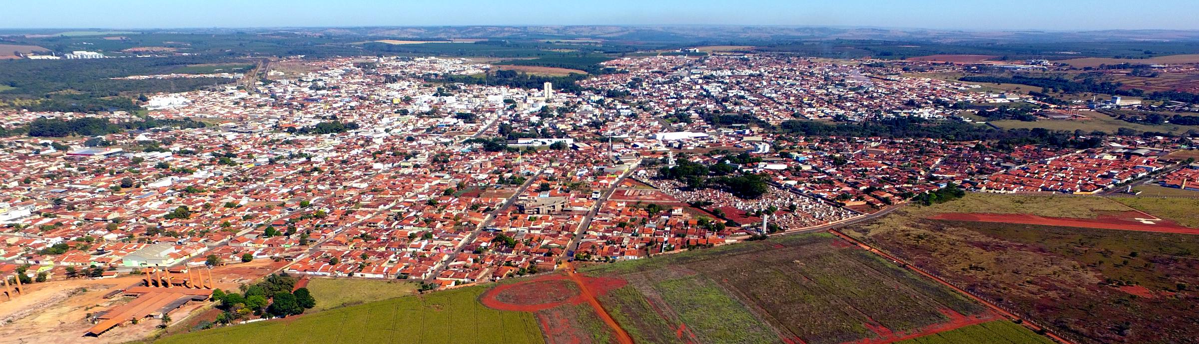 Vista aérea de Monte Carmelo: a cidade inteira vista do alto, com os canaviais em volta e o horizonte ao fundo